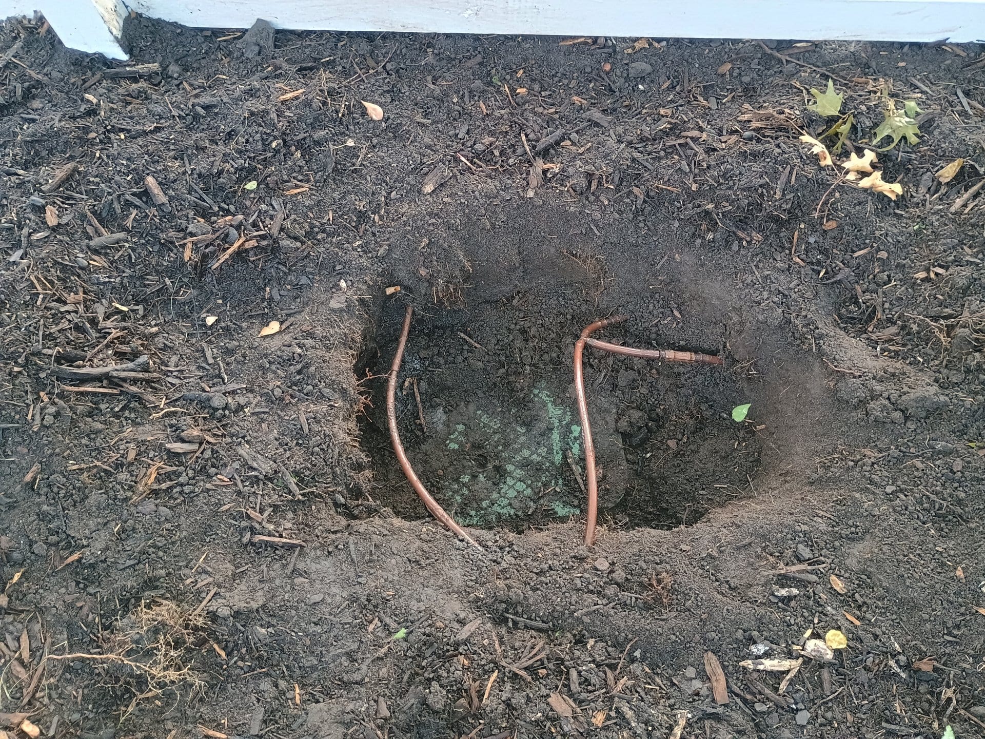 Buried irrigation valve box partially exposed after excavation in DFW clay soil