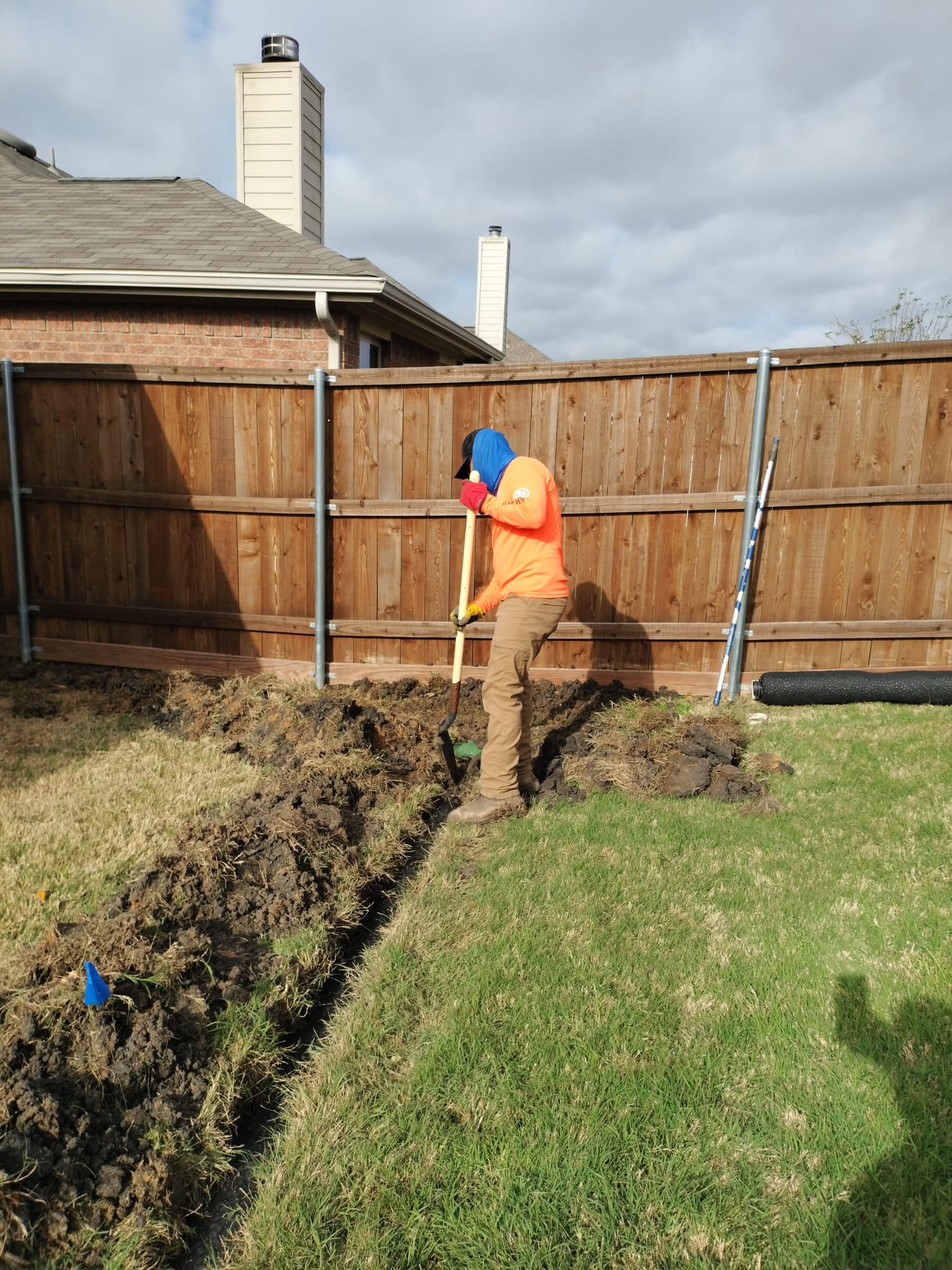 Hand-digging a drainage trench through clay soil in a DFW backyard