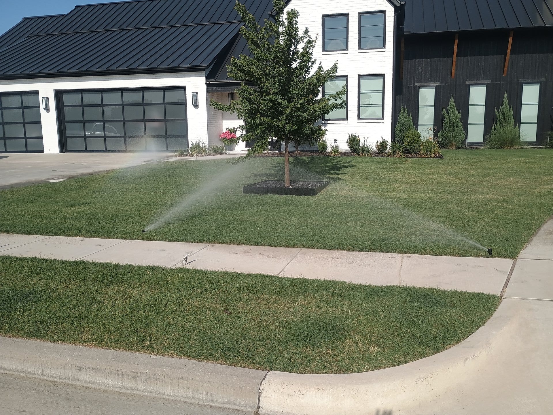 Rotor sprinklers running with efficient spray pattern in front of a modern home
